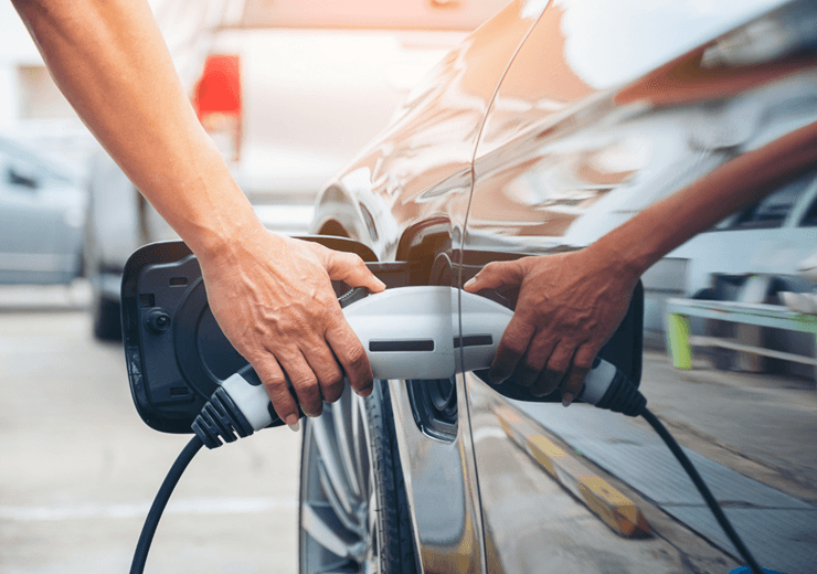 ©Adobstock Tongpatong Hand Hold Of Charging Modern Electric Car Battery On The Street Which Are The Future Of The Automobile, Close Up Of Power Supply Plugged Into An Electric Car Being Charged